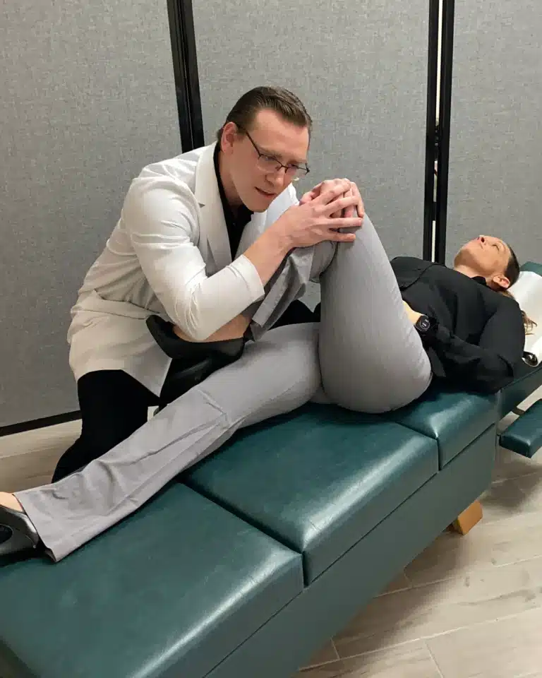 Dr. Michael Brandon, D.C., assessing knee and hip mobility on the treatment table