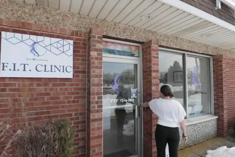 A visitor opening the front door under the F.I.T. Clinic sign at 8 Merchants Way, Colts Neck